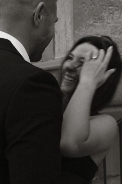 Candid black and white photo of a couple laughing together during their Michigan City engagement session at Washington Park Beach, captured by Rainstorm Photo & Video in a classic, documentary style.
