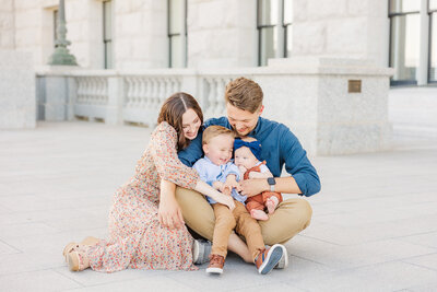 Family of 4 laughing together during their family session at the Utah State Capital.