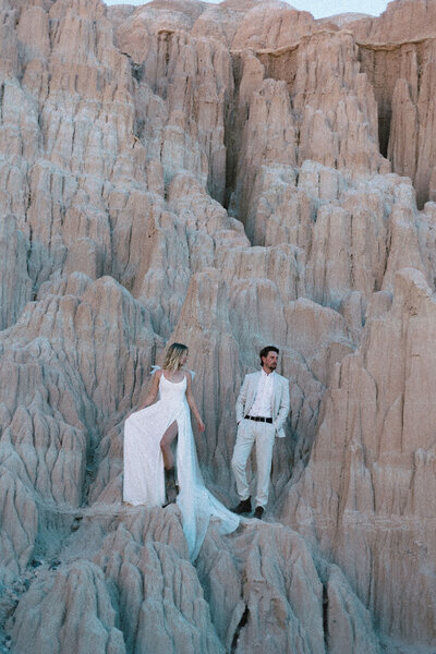 A wedding couple standing on rocks.