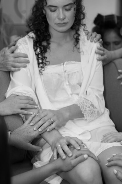 Bride cries tears of joy while friends pray over here with their hands on her