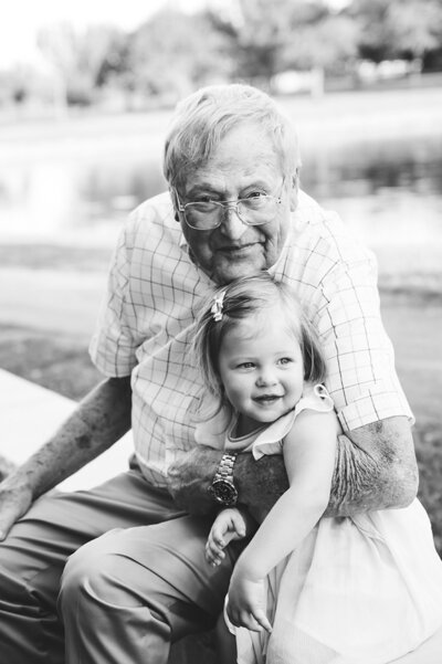 Grandpa holding toddler granddaughter both smiling and ineracting