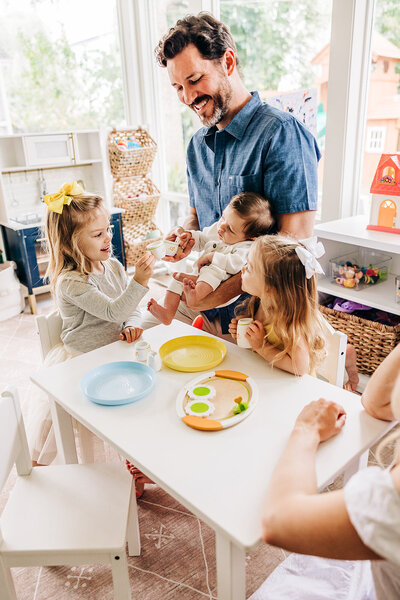 light airy photo of family giggling in home with newborn baby.