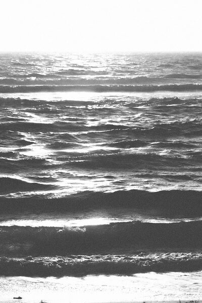 Aesthetic black and white photo of an ocean with sun glimmers
