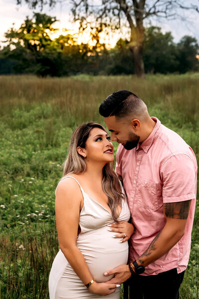 Connecticut maternity photographer captures expecting couple in golden hour field with sunset backdrop