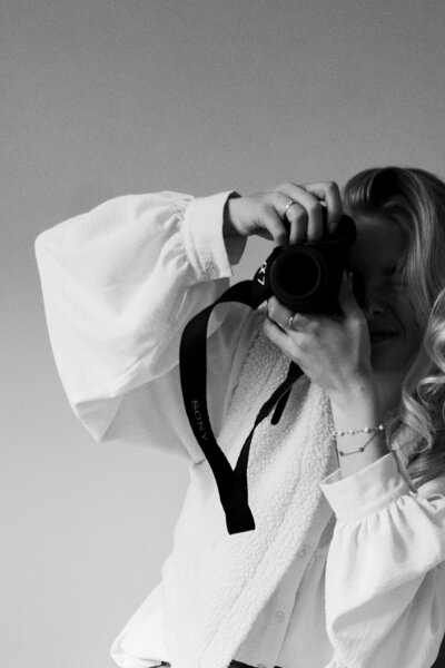 Een vrouw maakt een foto met een camera, gefocust en creatief in haar benadering van fotografie.