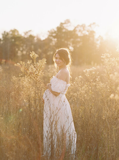 Pregnant woman in a field embracing her belly