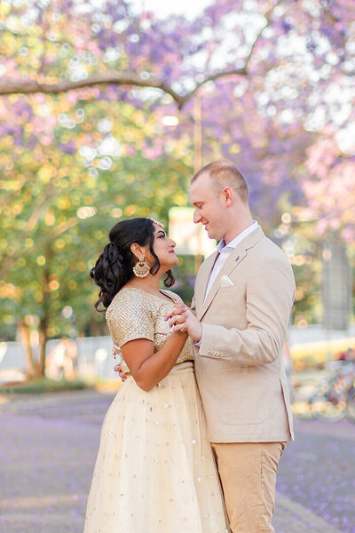 indian couple dancing in jacarandas for their engagement photos in UQ Brisbane