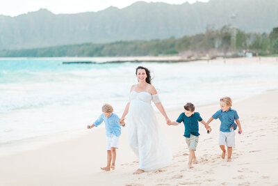 Expecting mother walking along Bellows beach with her three sons.