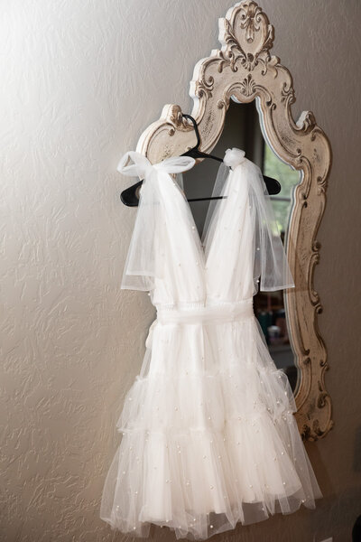 An Austin-based wedding photographer captures a stunning image of a white wedding dress hanging elegantly on a mirror.