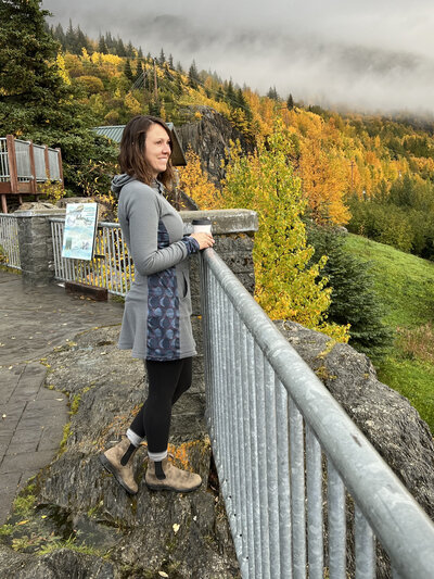 Becky, an elopement photographer, stands looking out over the views in Alaska.