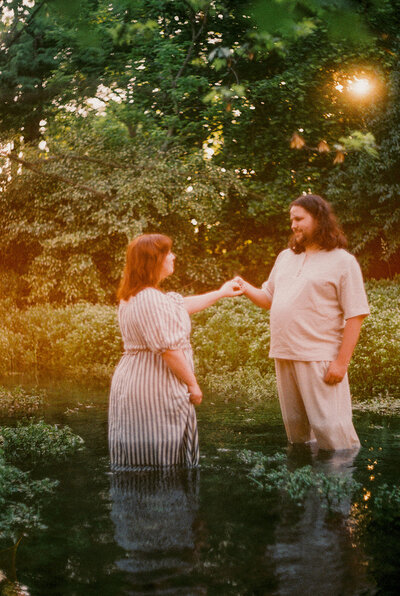 A dreamy, nature-filled engagement session with a couple standing in water, bathed in golden light, evoking romance and serenity.