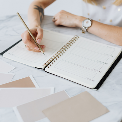 Photo of a woman's hands writing in a business planner. 