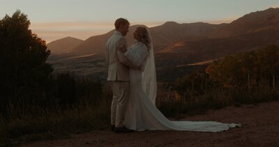 bride and groom holding each other with mountains in the background