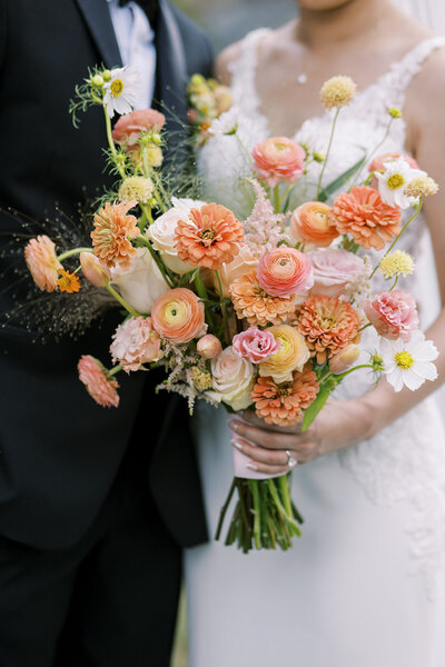 Bride holding a bright, warm floral bouquet