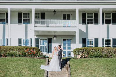 Bride and groom pose for a portrait by Scranton Wedding Photographer Eric Boylan in front of a white colonial mansion at Windridge Estate in Cazenovia, Ny
