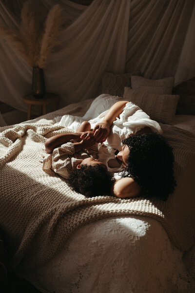 woman laying on bed with baby