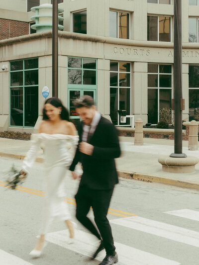 A bride and groom crossing the road shot in a blurry, film-style