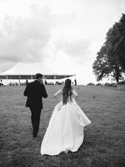 Bride and Groom walking towards their tented reception