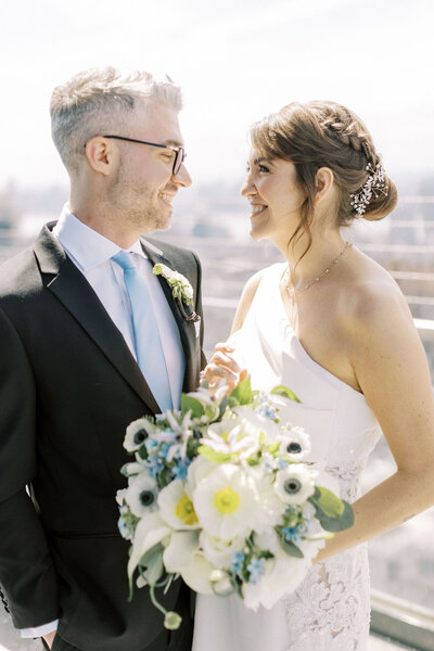 Bride and groom gazing into each others eyes on city rooftop