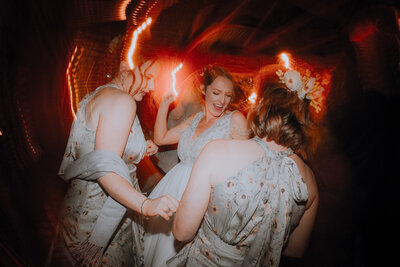 Bride on the dancefloor with her bridesmaids and the lights dragging in the background