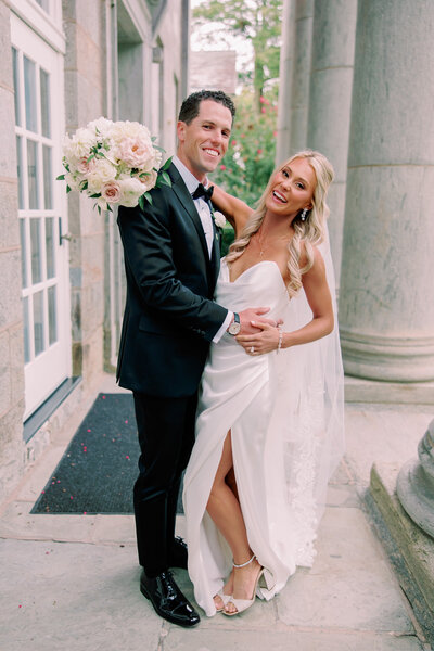 A newlywed couple smiling with their arms around each other 