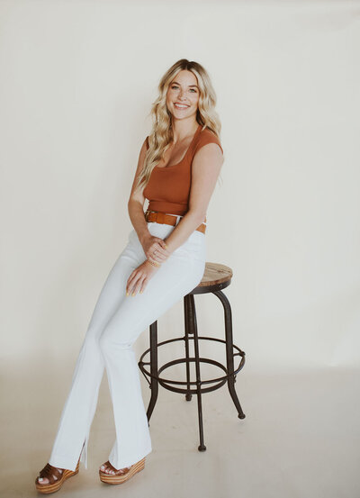 woman smiling while sitting on a stool