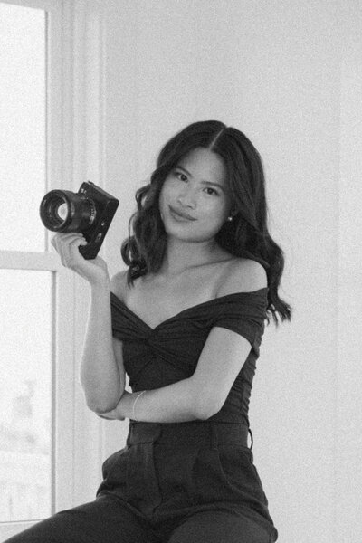 black and white mid-length shot of girl sitting holding a camera