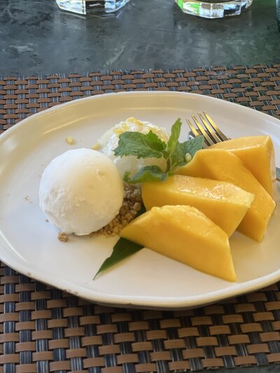 Plate of mango sticky rice with coconut ice cream and mint garnish
