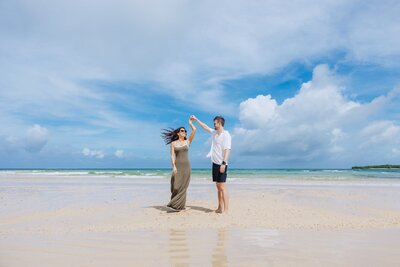 engaged couple twirling on beach