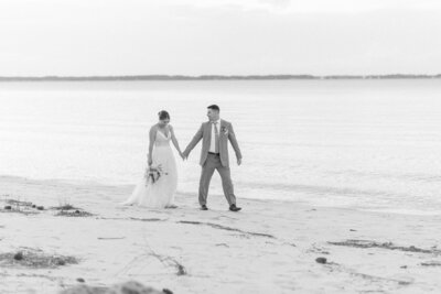 Bride and groom walking hand in hand on the beach