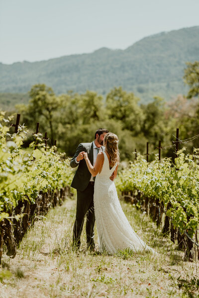Couple sharing a kiss in a Sonoma Valley vineyard on their wedding day