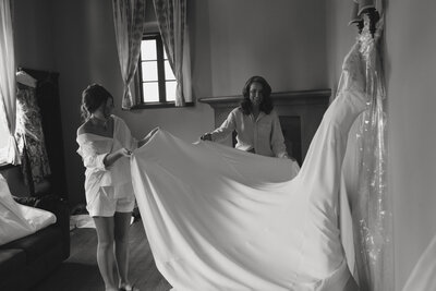 two women straightening bridal dress