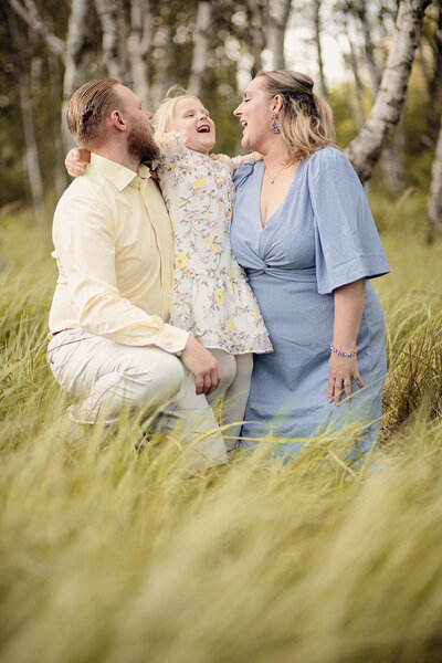 mamma och pappa tittar på sin dotter, alla skrattar