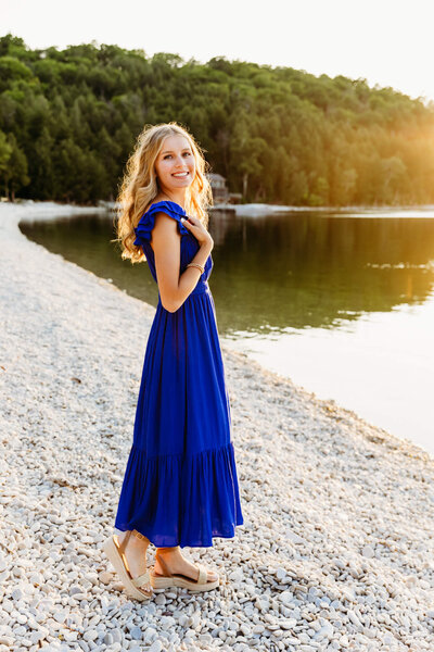 teen girl standing on a white stone beach  in Door County during golden hour for her Door County senior session