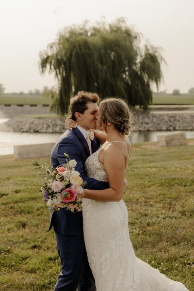 Bride and groom embrace tightly as they share a giddy kiss.