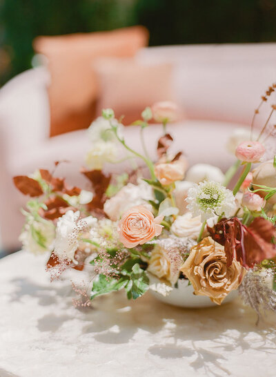 A modern bohemian wedding lounge centerpiece with fresh flowers and dried foliage