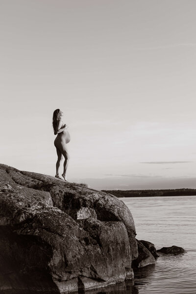 Gravidbild med naken kvinna ute vid vattnet