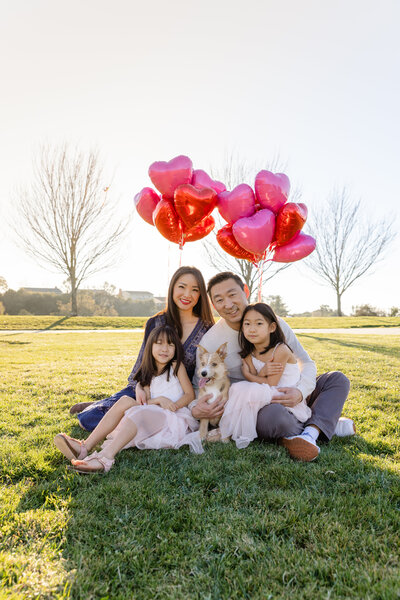 Family of 4 and their dog posing for portraits at a park in hayward with heart balloons, photo by Anastasiya Photography - San Francisco Photographer