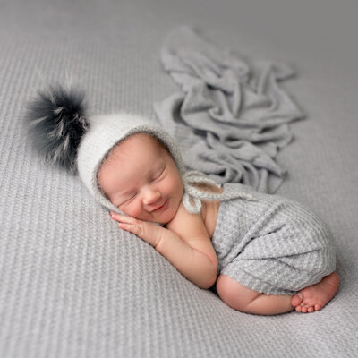 A smiling newborn on grey.