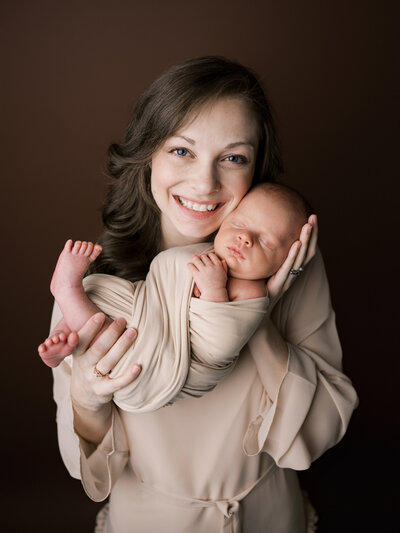 Mom holding newborn wrapped in tan blanket