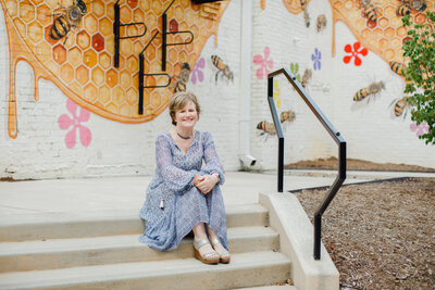 Woman in a periwinkle dress sitting on some stairs outside