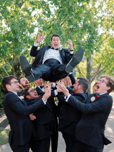 Groomsmen toss the groom into the air