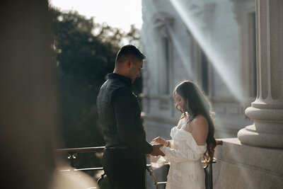A couple candidly interacts with each other on the top of the South Carolina State House steps. Golden hour light peeks in behind them for an cinematic moement.