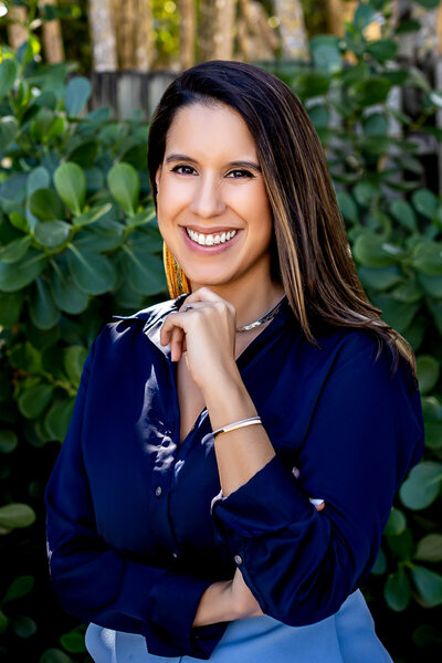 Headshot photo of a woman smiling with her hand up to her chin.
