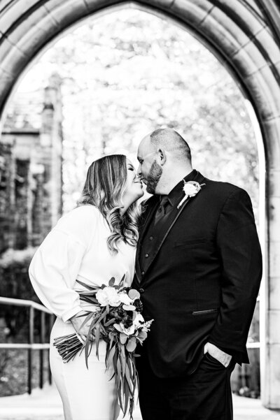 Bride and groom close together smiling standing under and arch at historic Nashville church