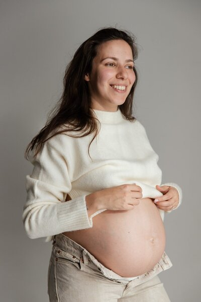 femme enceinte qui sourit pendant son shooting grossesse doux avec Studio Sensigraphie photographe maternité la tour du pin en Isère