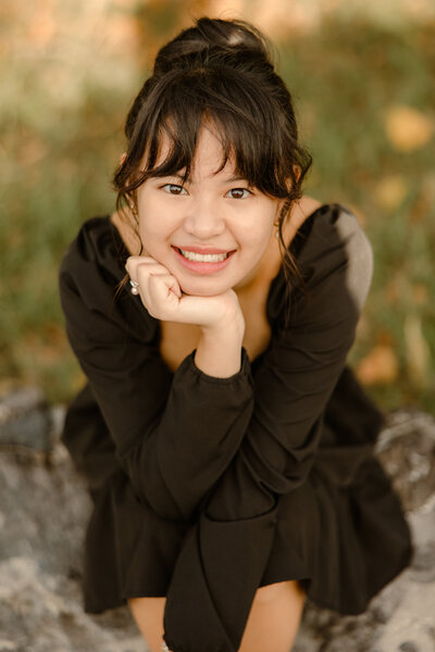 senior in black dress smiling at the camera