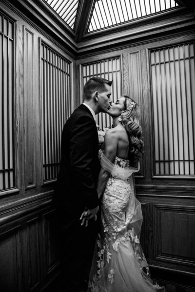 Bride and groom sharing a kiss in an ornate elevator at San Francisco City Hall, captured by San Francisco elopement photographer Kristin Smith.