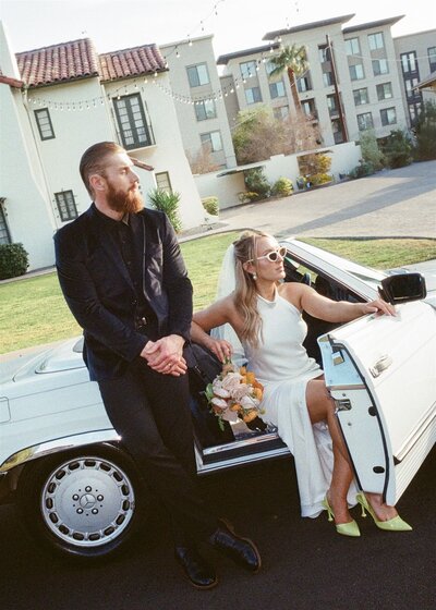 bride and groom in retro car in downtown Phoenix looking away from camera 