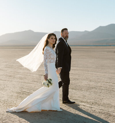 bride and groom walking together after eloping at a dry lake bed in nevada